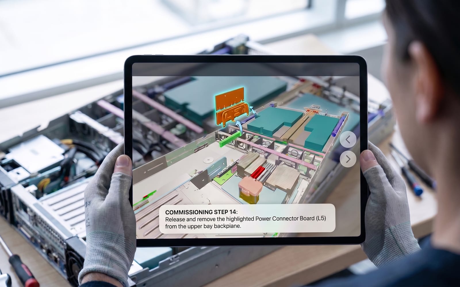 A technician in work gloves holds an iPad over an open server chassis on a bench; the Jig on screen is at commissioning step 14 and highlights the power connector board to remove